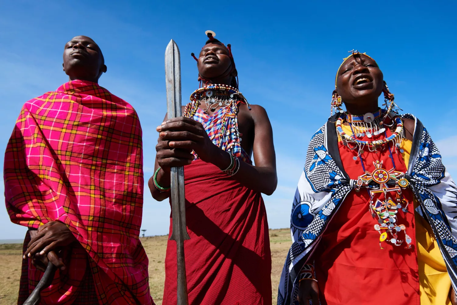 Group of Massai men and women singing and dancing, Masai Mara National Reserve, Kenya.